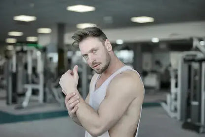 Man in gym flexing his arm muscles, enhancing strength on TRT with supplements.